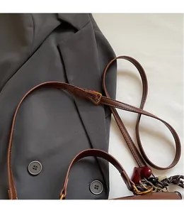 Détail de la bandoulière réglable en cuir marron avec boucle en métal doré et couture