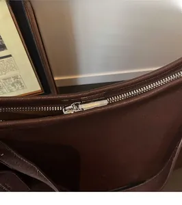 Detailed close-up of the smooth silver metal zipper on a dark brown leather shoulder bag