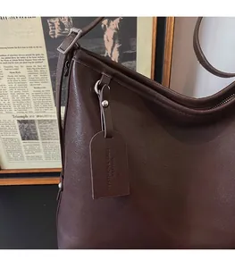 Detail of dark brown leather tote showing textured finish and fashion tag hanging on the side