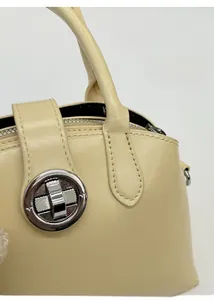 Macro view of a cream leather handbag featuring a silver ring buckle and handle detail