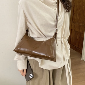 Detail of dark brown glossy leather shoulder bag with silver metal ring connector