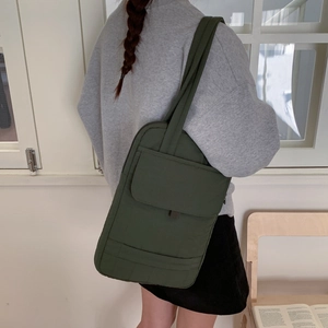 Detail of dark green waterproof nylon crossbody bag with large front flap pockets
