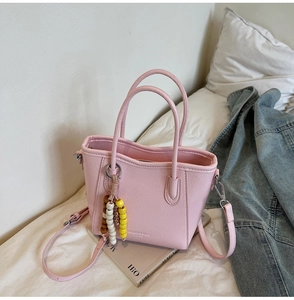 Pink leather bucket bag with top handles, fashion branding, and beaded charm detail