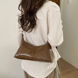 Detailed back view of a dark brown hobo bag with retro glossy finish on a model