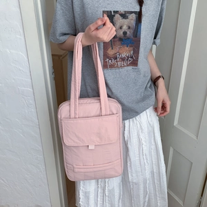 Detail of pink quilted nylon crossbody bag featuring front flap pocket and slim strap