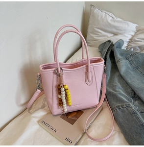 Detail of pink lychee leather bucket bag with wooden beads and fashion embossing