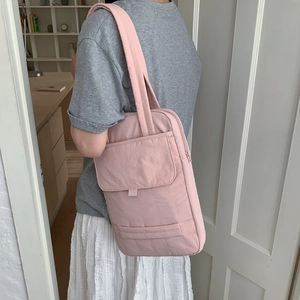 Detail of light pink quilted laptop bag showing stitching and flap pocket on shoulder