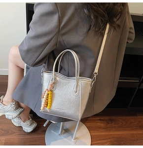 Silver textured bucket bag with colorful beads shown on person in a lifestyle setting