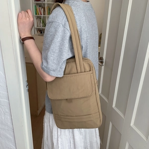 Detail of khaki nylon shoulder bag with vertical stitching and front flap pocket