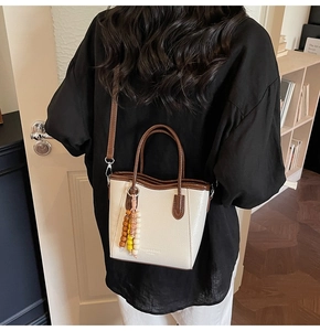 Model view showing the cream mini bucket bag with brown handles and bead detail