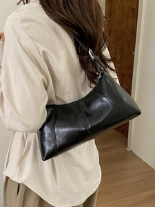 Minimalist black glossy shoulder bag with vintage dumpling shape and silver buckle strap