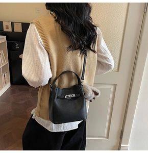 Detail of black lychee grain leather bucket bag with silver twist lock on shelf