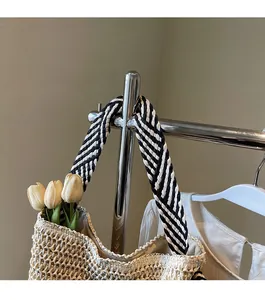 Close-up of wide black and white striped woven shoulder strap on a straw tote bag