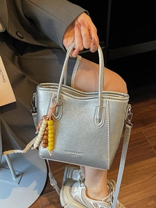 Chic silver bucket bag with metallic texture, top handles and adjustable strap