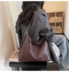 Detail of adjustable silver buckle and soft brown leather texture on a tote bag