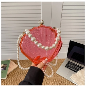 Pink shell-shaped acrylic handbag featuring a large pearl chain and gold ball clasp
