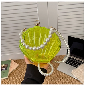 Detailed shot of a green acrylic shell bag featuring elegant large pearl strap accents