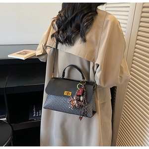 Détail d'un sac à main tissé bicolore avec fermoir rotatif doré et pendentif à fleurs