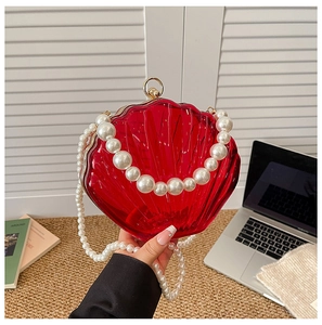 Detail of red acrylic shell evening bag featuring a faux pearl handle and gold ring clasp