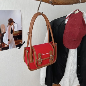 Détail d'un sac bandoulière vintage en toile rouge et cuir marron à double boucle