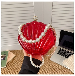 Detail of red acrylic shell evening bag with luxury pearl handle and metallic closure