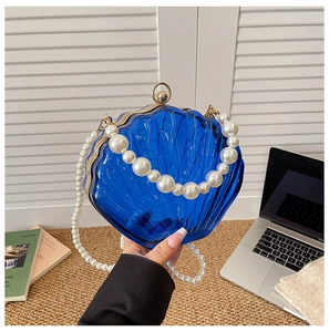 Detail of blue shell-shaped acrylic clutch with gold frame and pearl handle strap