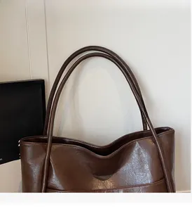 Dettaglio di una borsa tote vintage in pelle marrone scuro con manici lunghi resistenti
