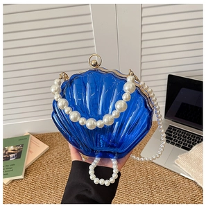 Detail of dark blue shell acrylic evening bag with pearl strap and gold metal ball clasp