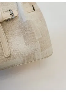 Detailansicht aus gewebtem Stoff und Lederbesatz mit Silberschnalle an der beigen Tasche