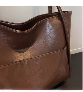 Dettaglio borsa tote marrone scuro con trama della pelle e cuciture della tasca frontale