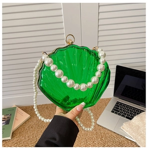 Close-up of green acrylic shell-shaped clutch bag featuring a luxurious pearl strap