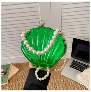 Detail of green acrylic shell evening bag with pearl strap and golden metal clasp
