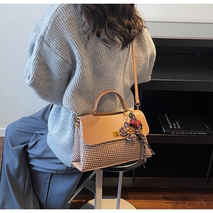 Détail du sac cabas vintage avec texture tissée, rabat en cuir marron et fermoir rotatif métal