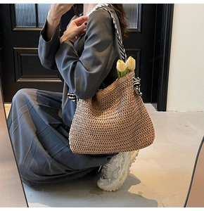 Detail of hand-woven straw tote bag with black and white striped ribbon and tulip decor