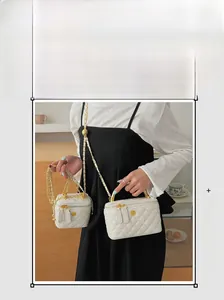 Close-up of white quilted leather box bags with golden chain and camellia logo