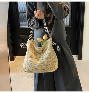 Détail d'un sac cabas en paille avec texture tissée et poignée à ruban rayé bicolore