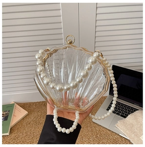 Detail of acrylic shell clutch bag featuring a shell texture and elegant pearl strap