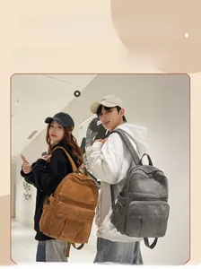 Detail of minimalist canvas backpacks in brown and dark grey with multiple pockets
