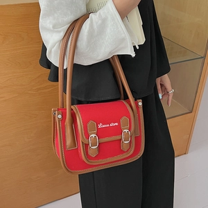 Détail d'un sac à bandoulière vintage en toile rouge avec garniture en cuir brun et boucles