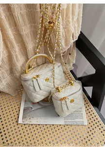 Detail of quilted leather texture and golden camellia ornament on white luxury handbag