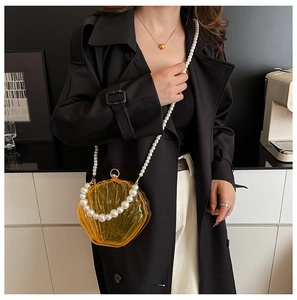 Chic amber translucent shell-shaped acrylic bag featuring elegant pearl shoulder straps