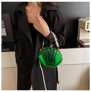 Detail of green acrylic shell bag featuring elegant pearl handle and long pearl shoulder strap