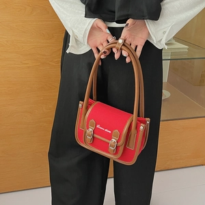 Vue détaillée d'un sac à bandoulière en toile rouge avec des finitions en cuir brun