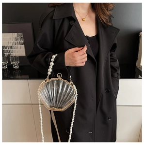 Detail of transparent shell-shaped evening bag with gold trim and pearl chain strap