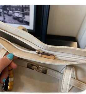 Close-up of smooth gold-tone zipper and decorative wooden beads on a white tote bag