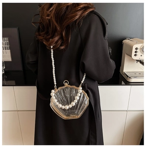 Detailed close-up of shell-shaped acrylic bag with elegant pearl straps and gold metal edges