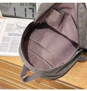 Internal view of a grey canvas backpack showing two open pockets and a zippered inner compartment