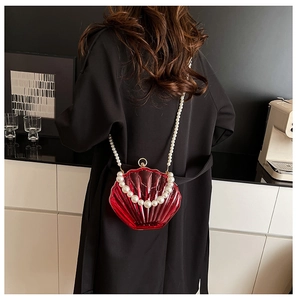 Detail of red shell-shaped acrylic bag featuring large decorative pearl handle