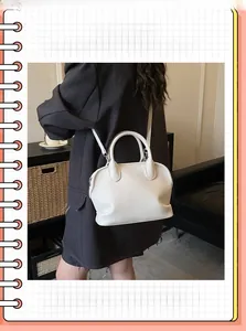 Detail of cream-white shell handbag showing lychee pattern texture and dual handles