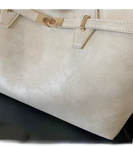 Detail of beige tote bag showing soft leather texture and light gold metal buckle